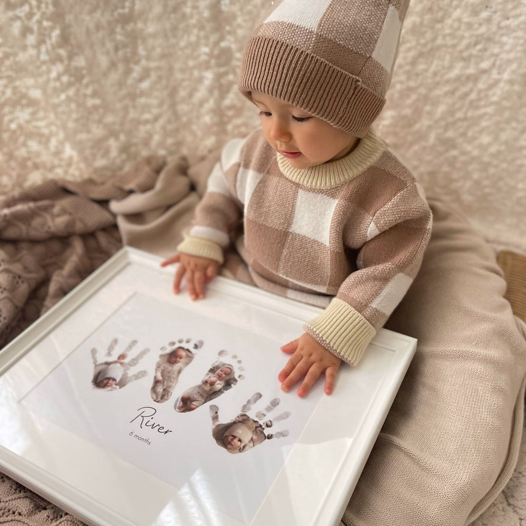 A baby is holding their Mimi Adores handprint and footprint keepsake. Two baby handprints and two baby footprints with photos of the baby expertly incorporated inside the prints. The baby keepsake is personalised with the baby’s name and age.